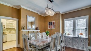 Une salle à manger avec une table en bois, des chaises blanches et un lustre.