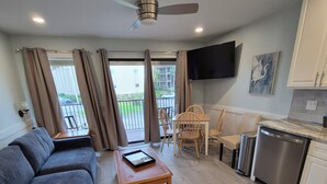 Ein Wohnzimmer mit einer Couch, einem Couchtisch und einem an der Wand montierten Fernseher.
