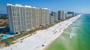 A beachfront hotel with multiple high-rise buildings, a sandy beach, and a clear blue ocean. - Beachfront King Suite/Big Balcony! (Panama City Beach)