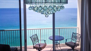 A balcony with a view of the ocean, a chandelier, and two chairs. - Beachfront King Suite/Big Balcony! (Panama City Beach)