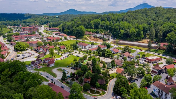 Ein Wohngebiet mit roten Dächern, einer zentralen Straße und umgebender Grünfläche.