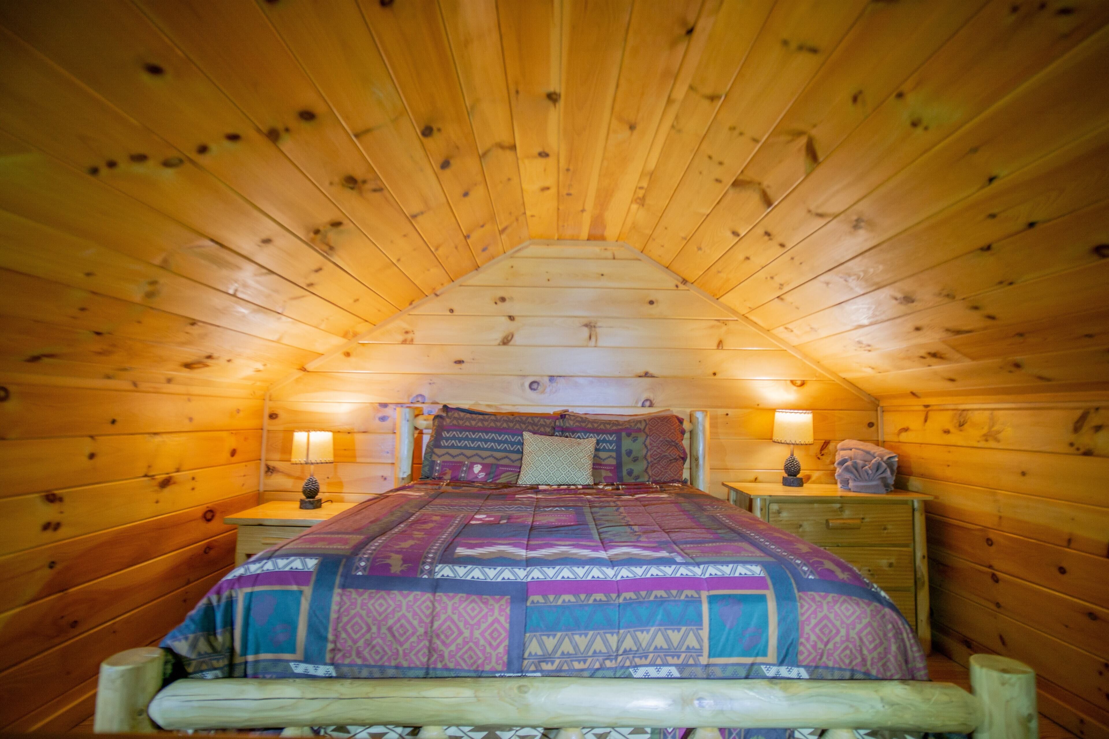A cozy, wooden-paneled bedroom with a bed, nightstands, and a lamp.