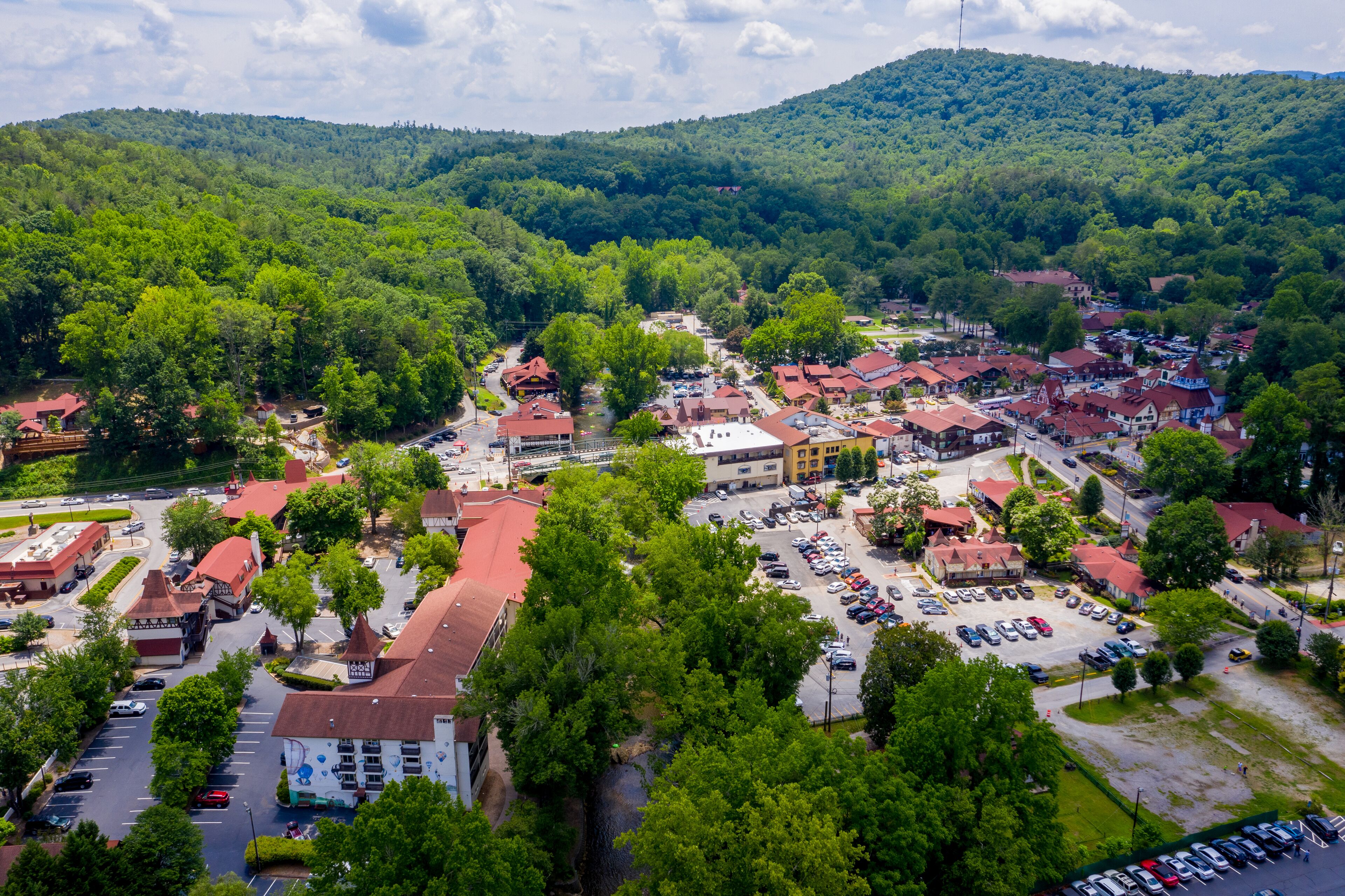 A town with a central square, surrounded by buildings with red roofs, and a parking lot in the foreground.
