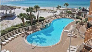 A pool area with a curved design, surrounded by lounge chairs and a view of the beach and ocean. - 16th floor 2 bedroom Beachfront at Pelican. Stunning View, 3 Pools, Beach Chairs (Destin)