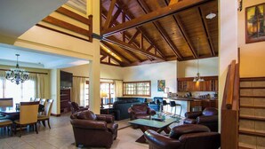 A spacious living area with leather sofas, a dining table, and a kitchen in the background. - Overlooks Los Suenos Marina 5BR (Playa Herradura)