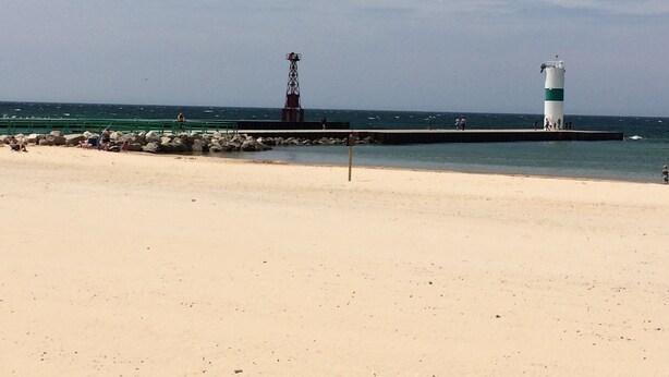 Une plage avec un phare et une digue rocheuse.