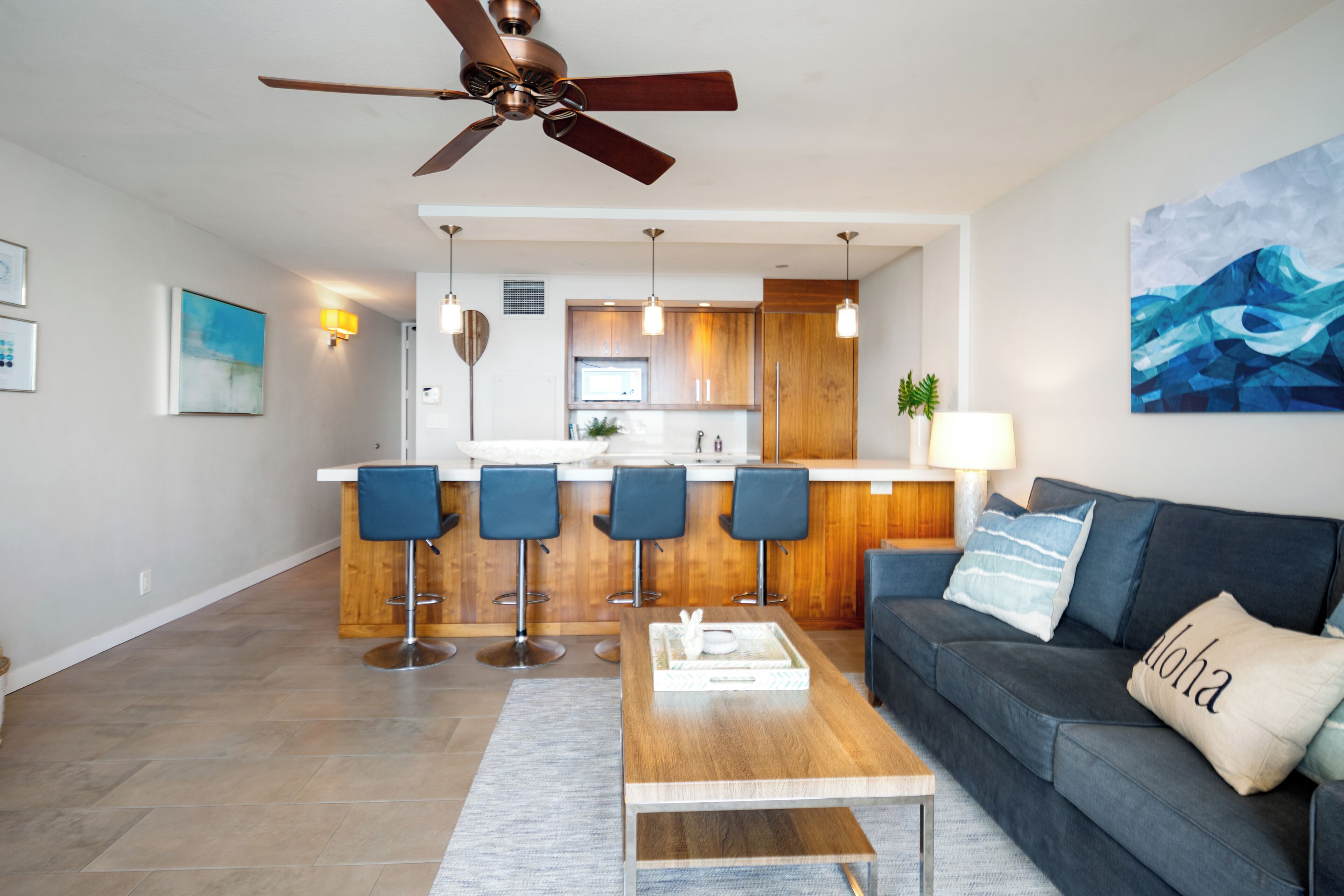 Un salon moderne avec un canapé gris foncé, une table basse en bois et un ventilateur de plafond.