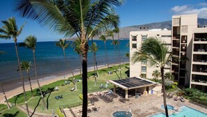 A hotel with a pool, palm trees, and a view of the ocean. - COMPLETELY REMODELED Sugar Beach Oceanfront Penthouse Sunset & Ocean View (Kihei)