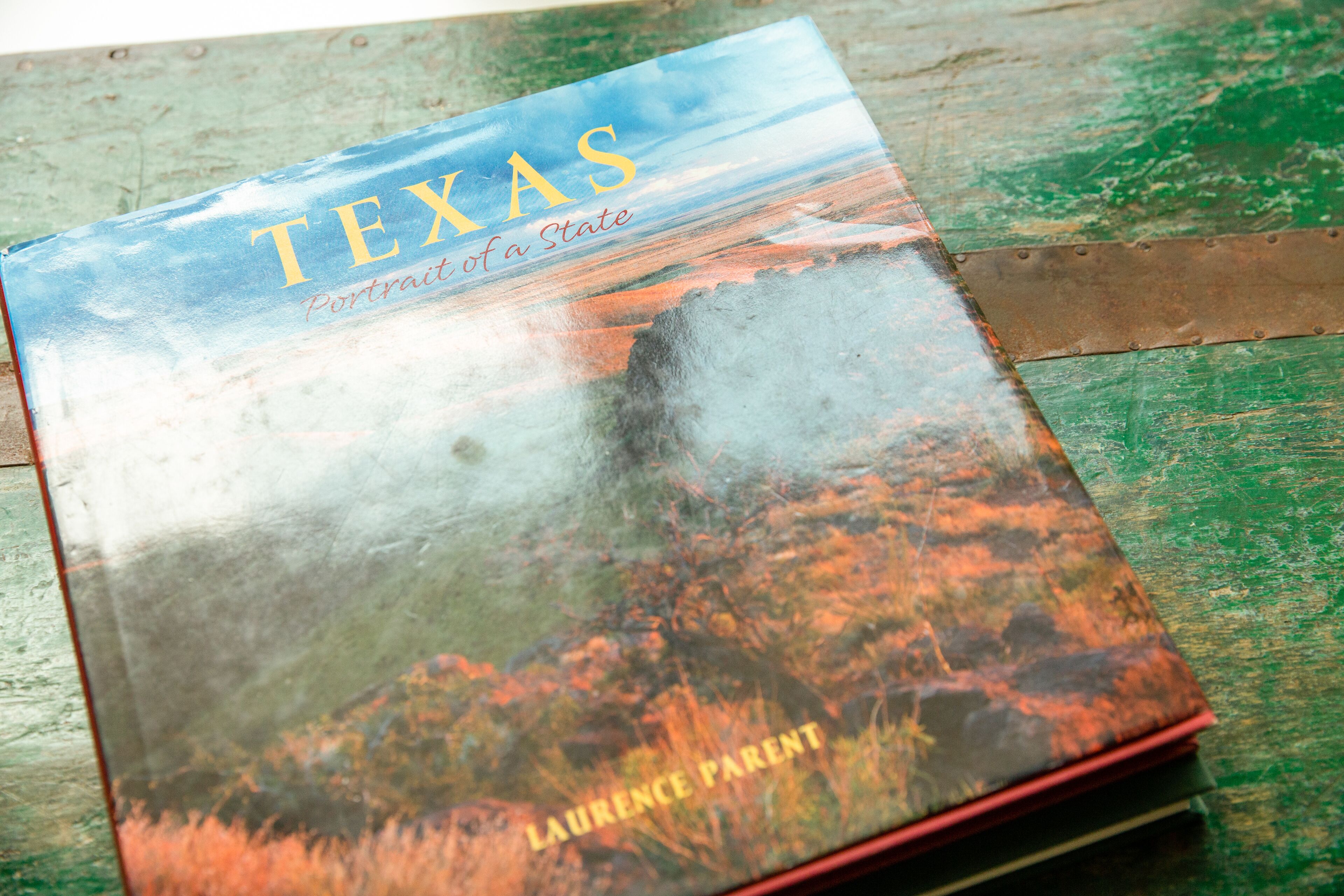 A book titled "Texas Portrait of a State" by Laurence Parent, placed on a wooden surface.