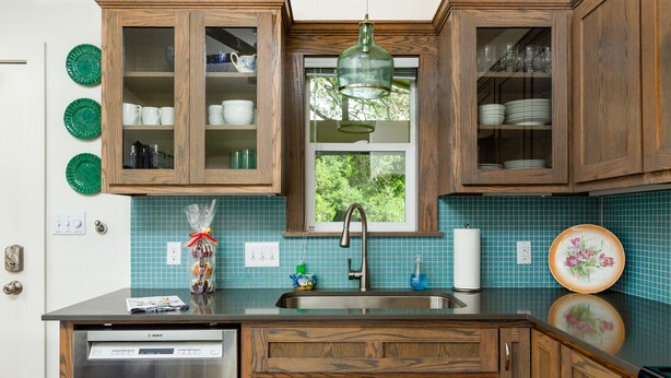 Cocina con muebles de madera, lavavajillas Bosch, ventana con vistas y un plato decorativo verde.