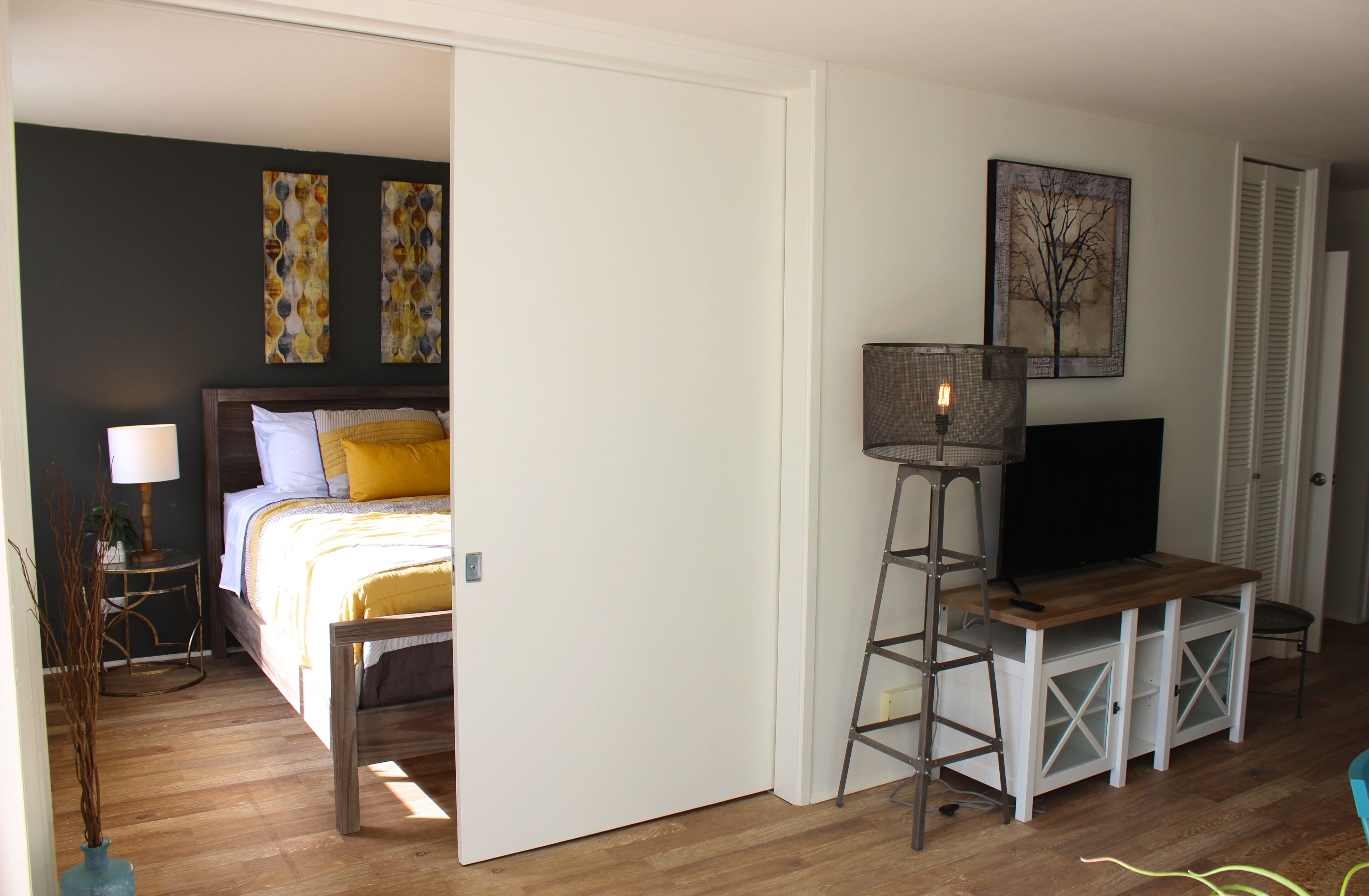 A bedroom with a bed, bedside table, lamp, and a TV on a stand.