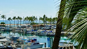 Un port de plaisance avec des bateaux amarrés, une plage en arrière-plan et des palmiers.