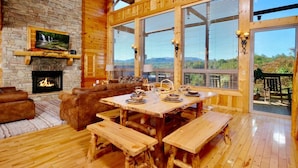 Un intérieur rustique avec une cheminée en pierre, une table à manger en bois et des bancs.