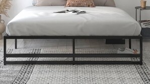 A minimalist bedroom with a bed, pillows, a bedside table, a vase, and a framed picture on the wall. - Downtown Traverse City Condo. Great Location. New King Bed  (Traverse City)