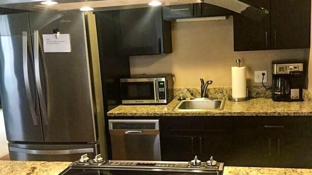 A modern kitchen with stainless steel appliances, a built-in microwave, a sink, and a coffee maker. - Downtown Traverse City Condo. Great Location. New King Bed  (Traverse City)