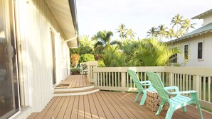 A wooden deck with a white railing, two green chairs, and a small table.