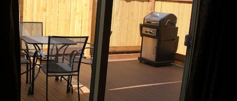 Eine Terrasse im Freien mit Holzboden, Metallstühlen und einem Grill.