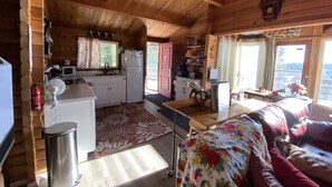 Interno di una baita in legno con cucina, sala da pranzo e soggiorno.