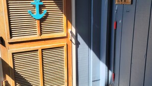 Una porta in legno con una decorazione ad ancora blu, una targa con un numero e un tappetino.