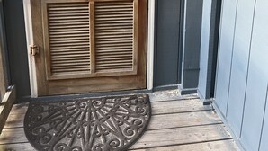 Una porta di legno con una chiusura in metallo e un cartello di benvenuto.