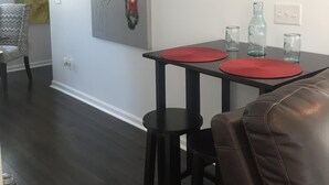 A dining area with a table set for two, a chair, and a wall-mounted thermostat. - Mayfaire, 3 miles to Wrightsville Beach. Very convenient  (Wilmington)