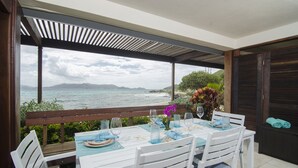 A dining area with a view of the sea and mountains, featuring a table set for two with a view. - Beach Resort  Walk-Out Patio with St. John Views (St Thomas)