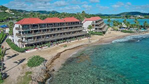 A hotel with multiple floors, a red roof, and a beachside location. - Beach Resort  Walk-Out Patio with St. John Views (St Thomas)