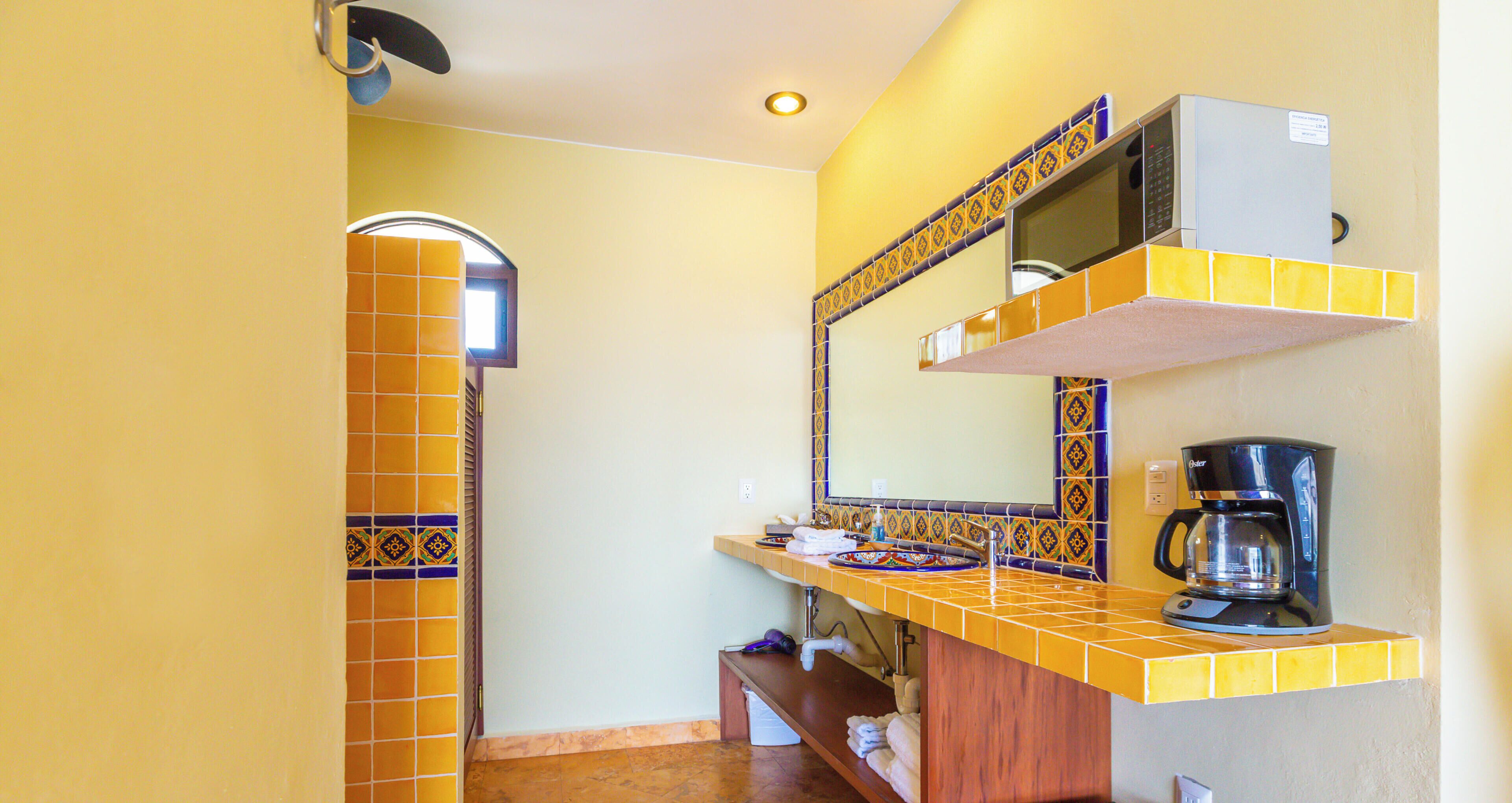 A compact kitchen with a microwave, coffee maker, and a sink.