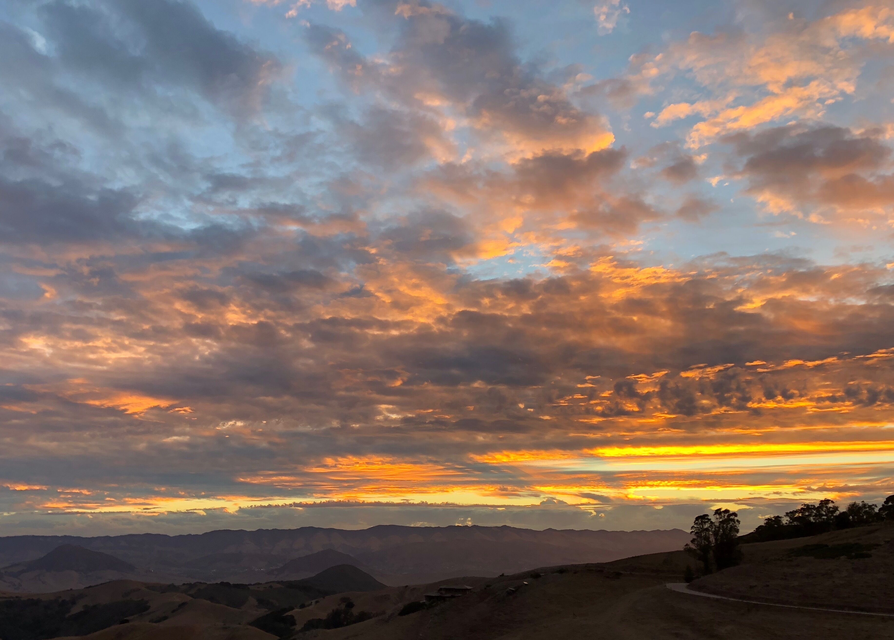 A sunset over a mountainous landscape with a dirt road.