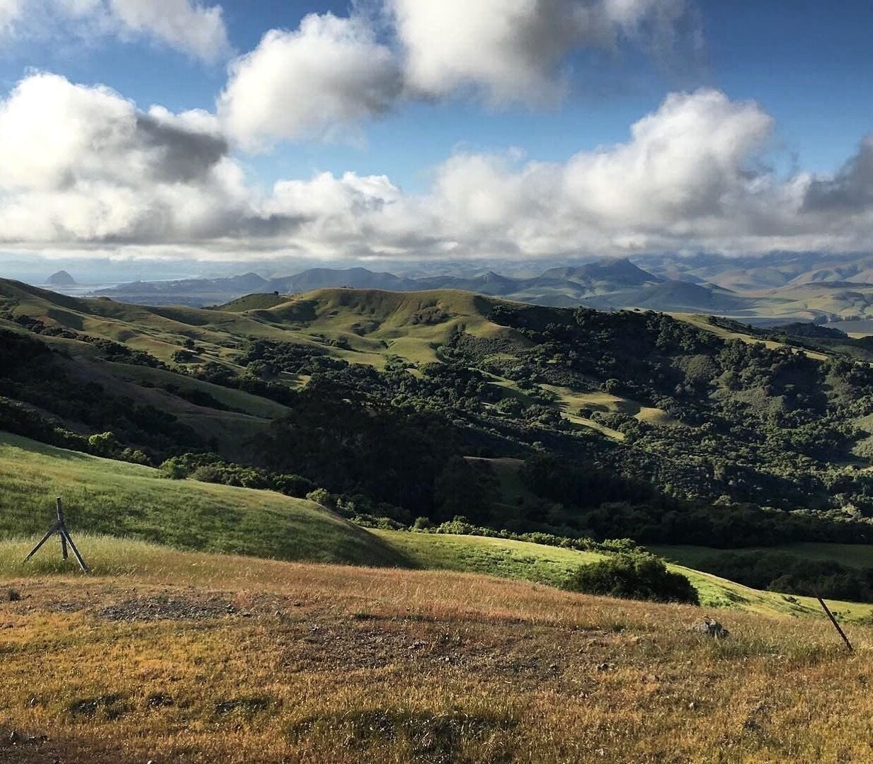 Rolling hills with a tripod in the foreground, suggesting a scenic outdoor location.