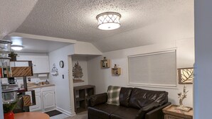 En kompakt opholdsstue med tekøkken, spiseplads og siddeområde med sofa og stole.