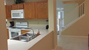 A kitchen with wooden cabinets, a microwave, a stove, and a sink.