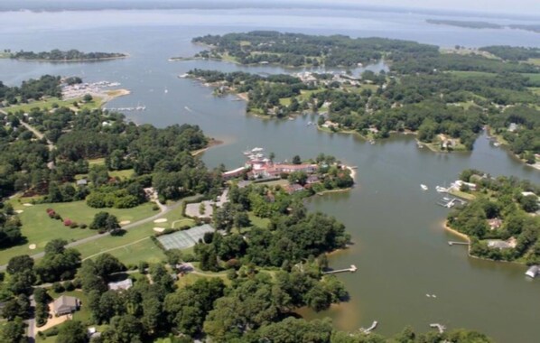An aerial view of a lakeside property with multiple docks, a golf course, and residential buildings.