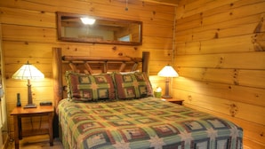 A wooden cabin room with a bed, two nightstands, and two lamps.