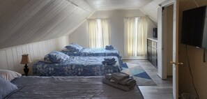 Una habitación con dos camas, televisión y armario.