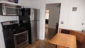 A kitchen with a stove, oven, microwave, and refrigerator. There is a wooden dining table with a bench. - Amazing Lake View Cottage with Game room for Kids of all ages (Sodus Point)