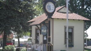 A small building with a clock, a bench, and a flower bed. - Amazing Lake View Cottage with Game room for Kids of all ages (Sodus Point)