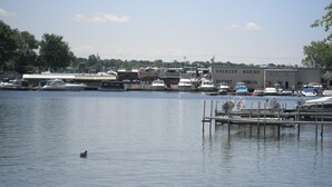 A marina with boats docked, a building labeled "KRENZER MARINE," and a duck swimming in the water. - Amazing Lake View Cottage with Game room for Kids of all ages (Sodus Point)