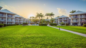 A resort with multiple two-story buildings, a well-maintained lawn, and palm trees.