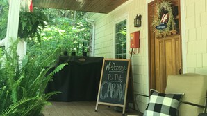 A wooden porch with a black table and a sign that reads "Welcome to the Cabin."