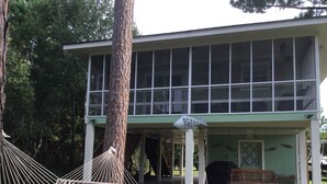 Un bâtiment moderne doté de grandes fenêtres, d’un patio couvert et d’un hamac.