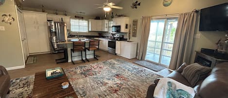 A spacious living area with a wooden dining table, a sofa, and a large rug.