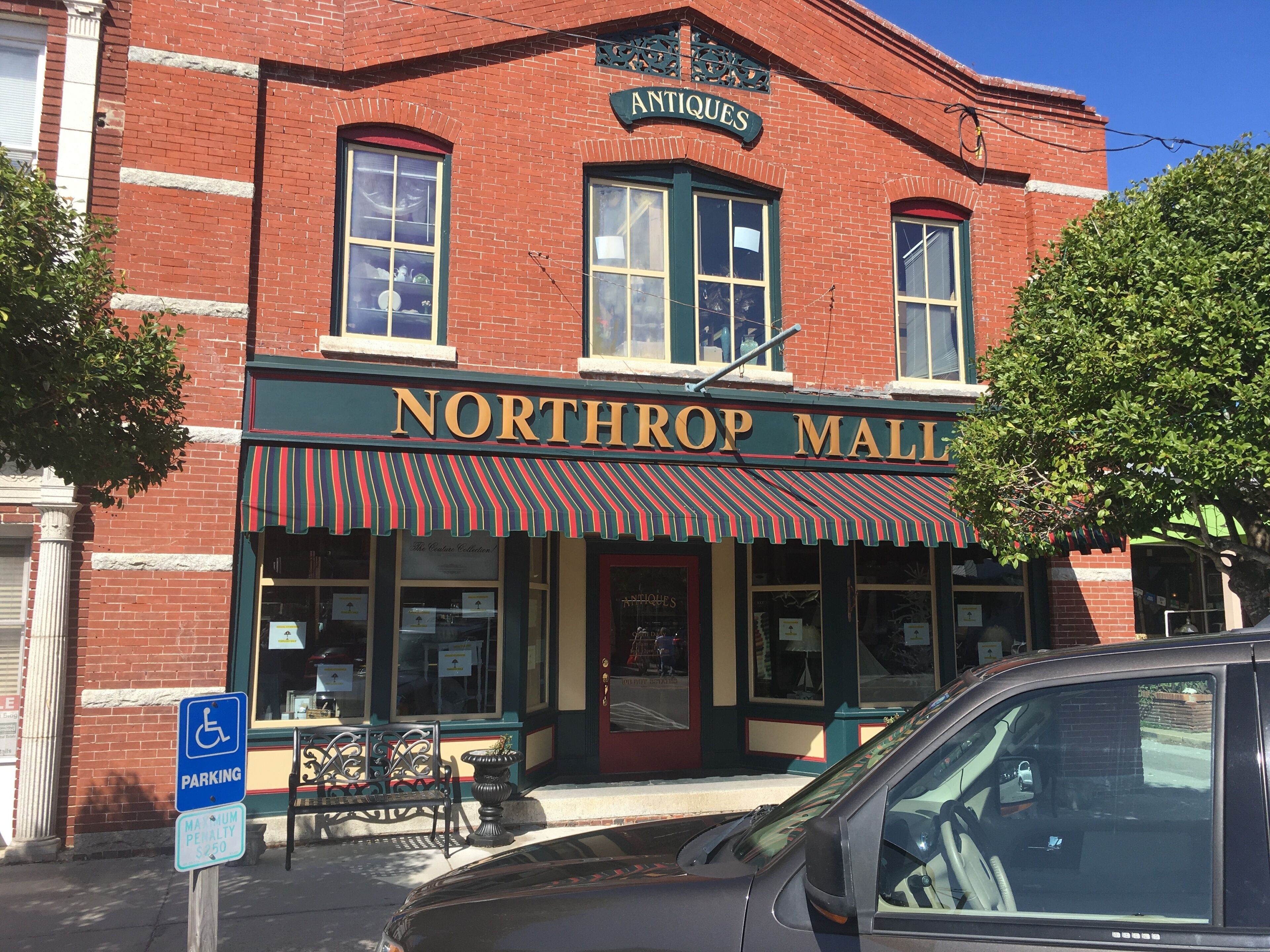 A brick building with a storefront labeled "NORTHROP MALL" and "ANTIQUES".