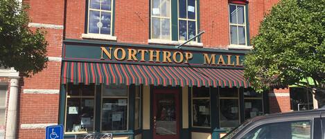 A brick building with a storefront labeled "NORTHROP MALL" and "ANTIQUES".