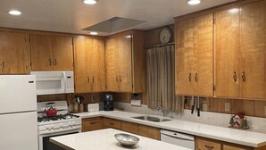 A kitchen with wooden cabinets, a white refrigerator, a stove, a microwave, a sink, and a small island with stools.