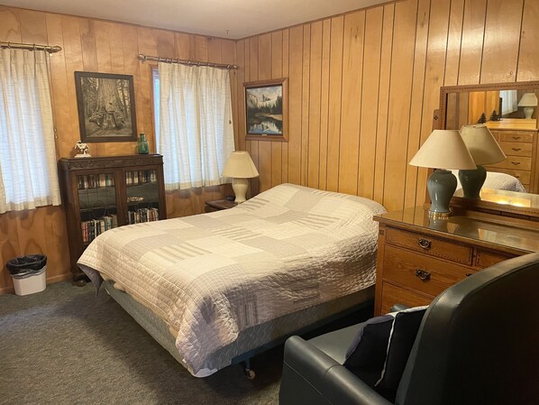 A bedroom with a bed, a dresser, a mirror, and a bookshelf.