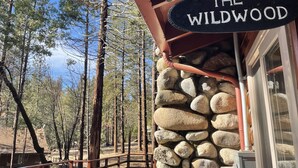 A rustic wooden deck with a stone wall and a sign reading "The Wildwood".