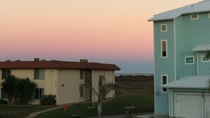 Un barrio residencial con dos casas, una beige y otra azul claro, bajo un cielo despejado con una luna visible.