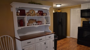 Una cocina con muebles de cocina blancos, un refrigerador negro y un microondas.