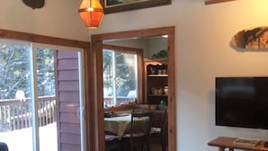 Een gezellige woonkamer met een houten salontafel, een televisie op een houten kast, en een schilderij van een zeelandschap.